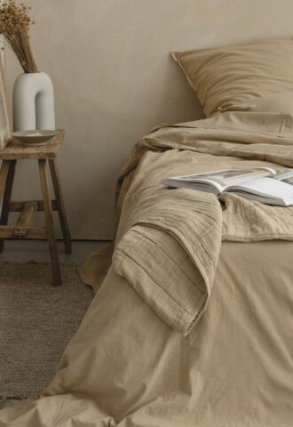 Chambre beige avec lit et livres ouverts.