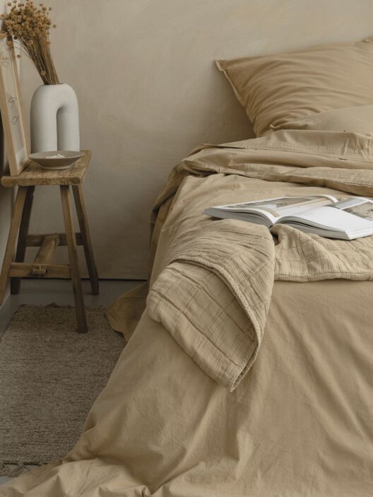 Chambre beige avec lit et livres ouverts.