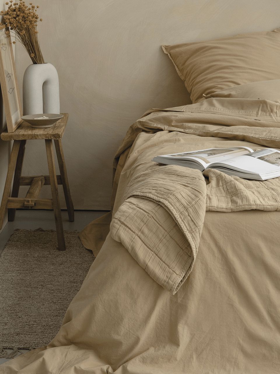Chambre beige avec lit et livres ouverts.