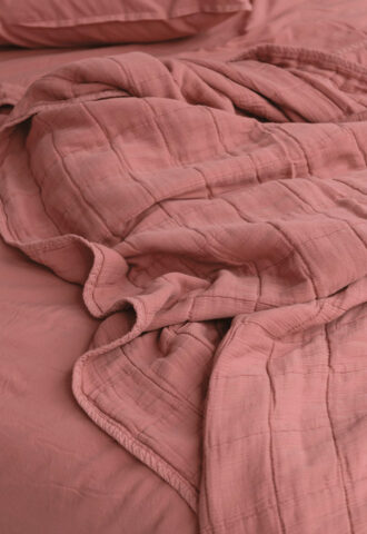 Drapé de lit en tissu rose texturé.