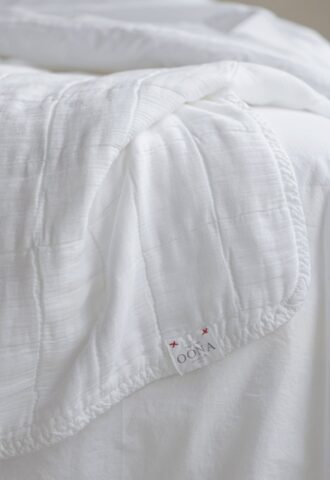 Couverture blanche en tissu sur un lit.