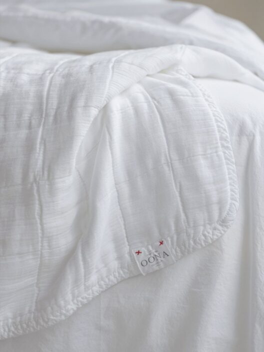 Couverture blanche en tissu sur un lit.