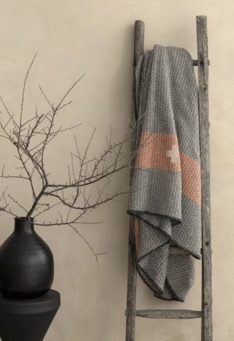 Échelle avec plaid et vase décoratif.