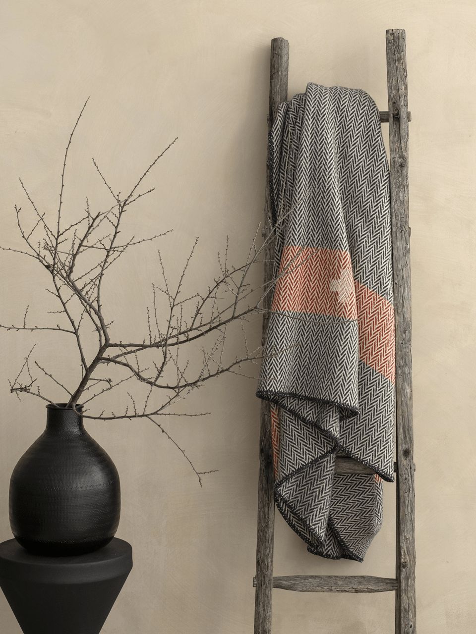 Échelle avec plaid et vase décoratif.