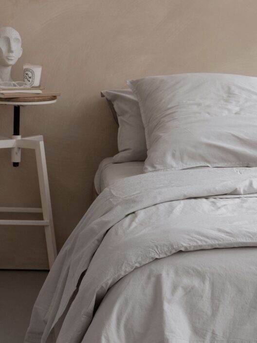 Lit avec oreillers et table de chevet minimaliste.