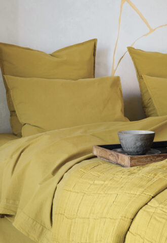 Chambre avec literie jaune et plateau.