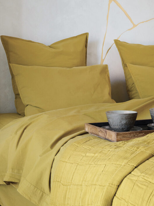 Chambre avec literie jaune et plateau.