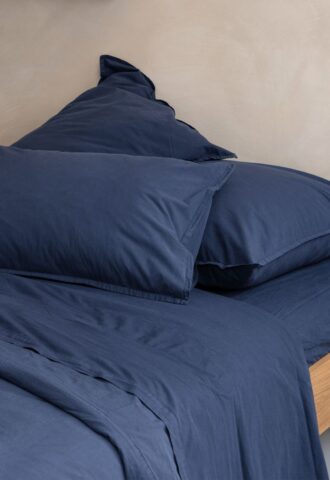 Parure de lit bleue sur un lit en bois.