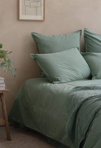 Lit avec draps verts dans chambre moderne.