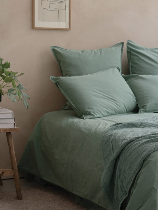 Lit avec draps verts dans chambre moderne.