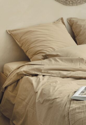 Lit beige avec coussins.