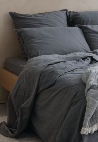 Lit avec draps et oreillers gris.