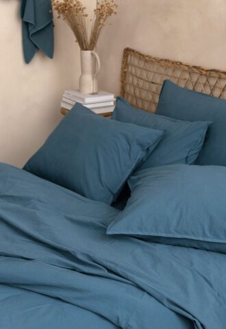 Lit avec oreillers bleus et vase décoratif.