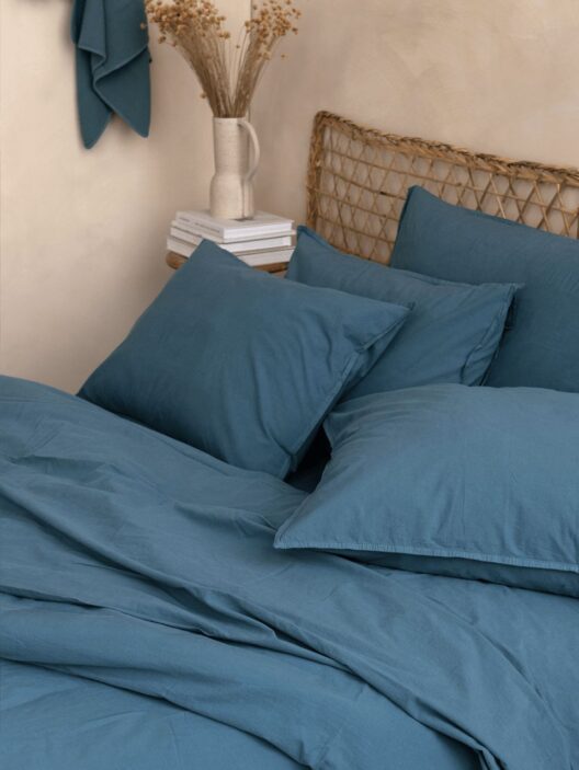 Lit avec oreillers bleus et vase décoratif.