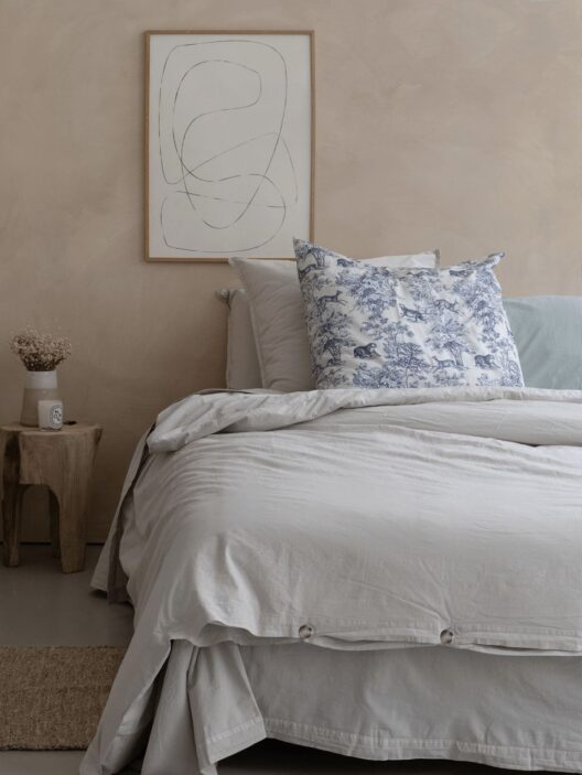 Chambre minimaliste avec lit et œuvre abstraite.