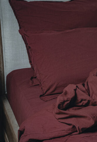 Literie en lin bordeaux sur un lit.