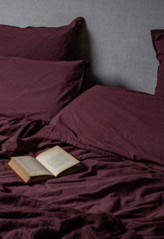 Lit avec couverture bordeaux et livre ouvert.