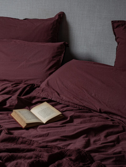 Lit avec couverture bordeaux et livre ouvert.