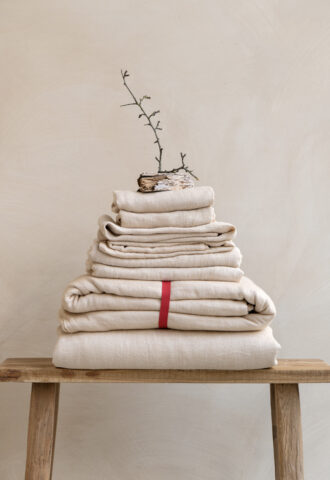 Stack of folded beige linens on a bench