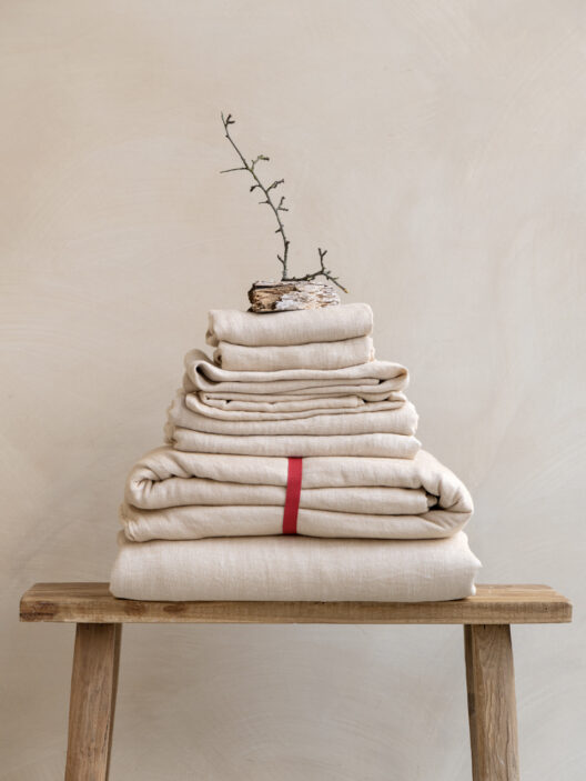 Stack of folded beige linens on a bench