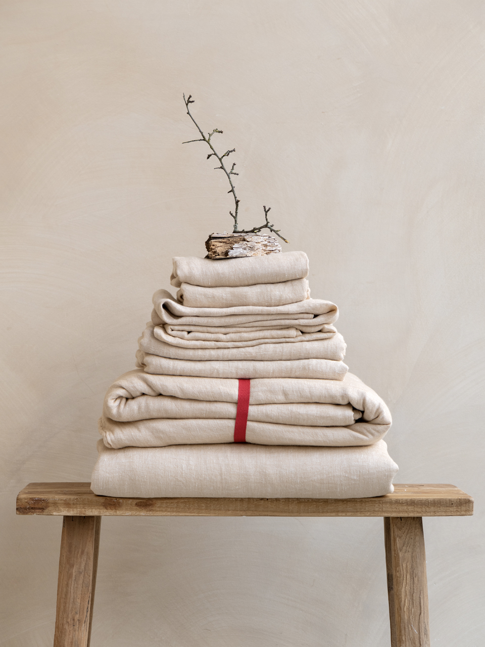 Stack of folded beige linens on a bench