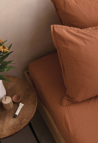Lit aux draps terracotta et table de chevet