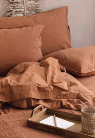 Lit avec linge de lit terracotta et plateau