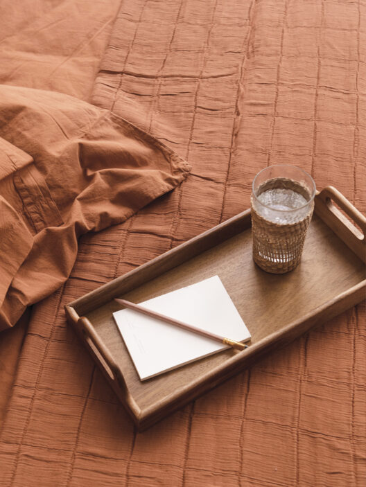 Plateau en bois avec carnet et verre d’eau
