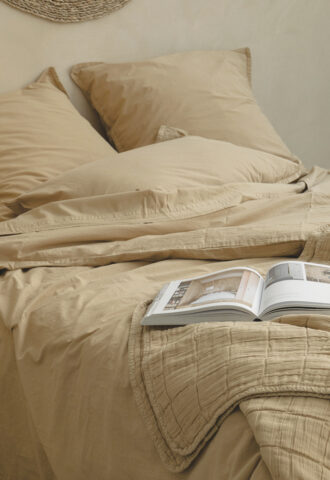 Lit beige avec livre ouvert et coussins