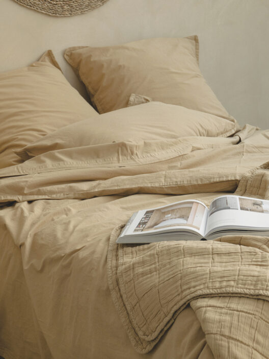 Lit beige avec livre ouvert et coussins