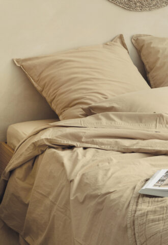 Lit beige avec coussins et draps en coton