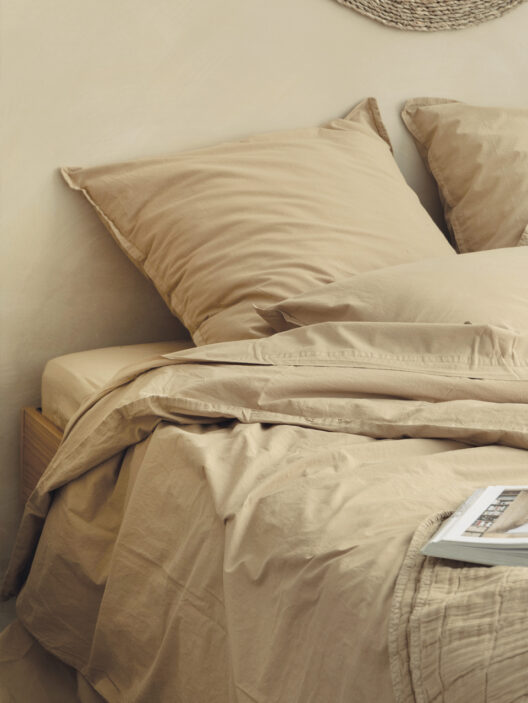 Lit beige avec coussins et draps en coton